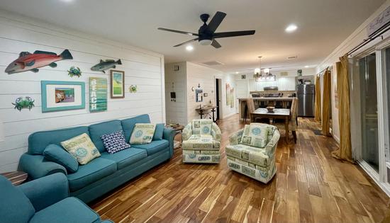 Coastal living room with sofa, seating area, and open kitchen in Rockport vacation rental