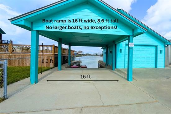 Covered canal-front boat ramp in Rockport, Texas with concrete driveway and access to the water, showing clearance and width for boat launching.