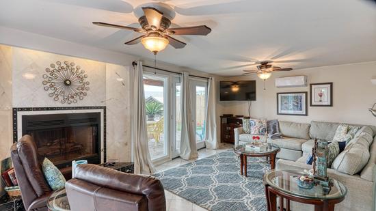 Living room with sectional sofa, two leather recliners, fireplace, wall-mounted TV, and glass doors to an outdoor patio.