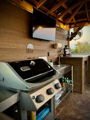 LARGE GAS GRILL - 50" TV - ICE MAKER - STAINLESS STEEL SINK - FOOD PREP/SERVICE AREA - GRILLING TOOLS & SEASONING PROVIDED - CLEANING SUPPLIES - UNLIMITED FIREWOOD - OUTDOOR FAN - CORN HOLE AND MORE