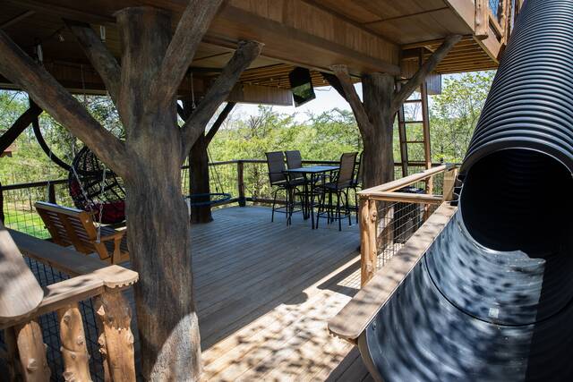 Lower porch features swings, rope climbs, 50" flat screen, table top seating for 4, secret ladder to access the escape hatch so you can jump on the 20 ft. slide down!