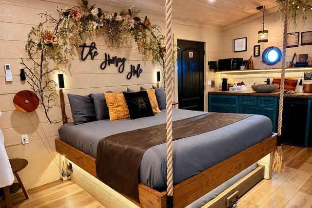 King bed with decorative rope posts, floral arch, and The Honey Hole sign above the headboard.