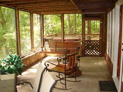 screened porch off living room with table and chairs and hot tub on deck
