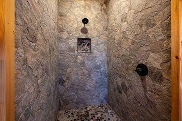 Cabin bath with stone wall shower.
